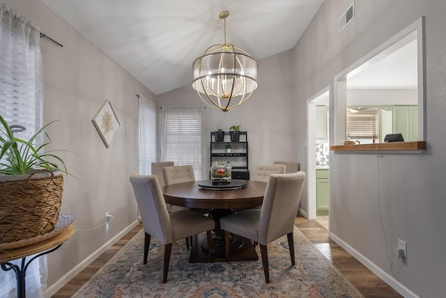 dining room featuring an inviting chandelier, lofted ceiling, and wood-type flooring