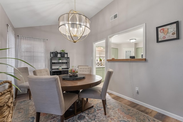 dining room with vaulted ceiling, plenty of natural light, a chandelier, and wood-type flooring