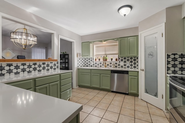 kitchen featuring backsplash, hanging light fixtures, appliances with stainless steel finishes, green cabinetry, and light tile patterned floors