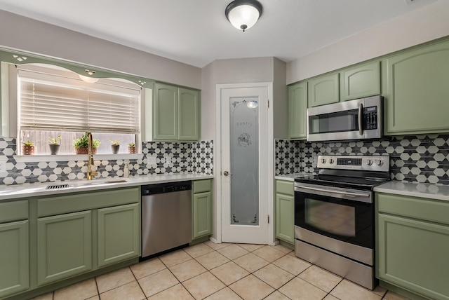 kitchen with sink, appliances with stainless steel finishes, green cabinets, and light tile patterned flooring