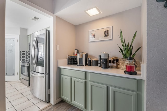 kitchen with light tile patterned floors, stainless steel appliances, and green cabinets