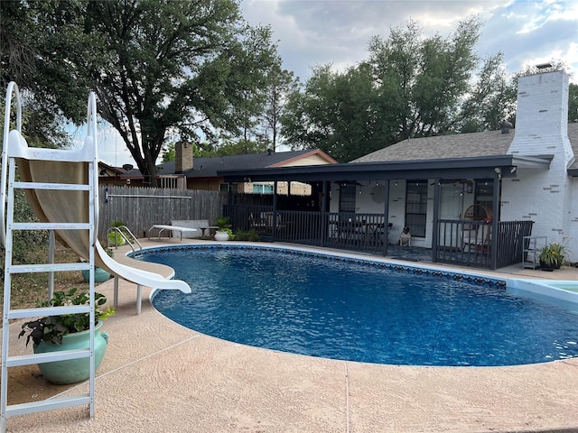 view of swimming pool with a water slide and a patio