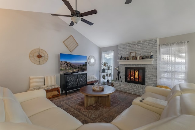 living room featuring lofted ceiling, ceiling fan, a brick fireplace, and a wealth of natural light