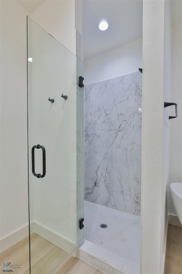 bathroom featuring hardwood / wood-style floors and a shower with door