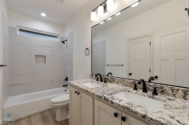 full bathroom featuring toilet, tiled shower / bath combo, vanity, and hardwood / wood-style flooring