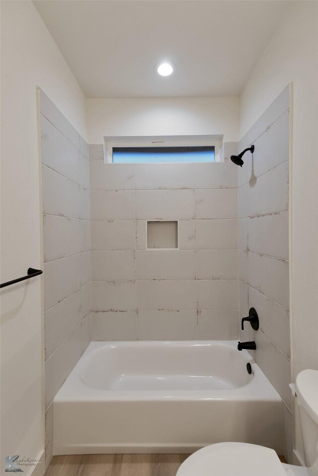 bathroom with toilet, tiled shower / bath, and hardwood / wood-style floors