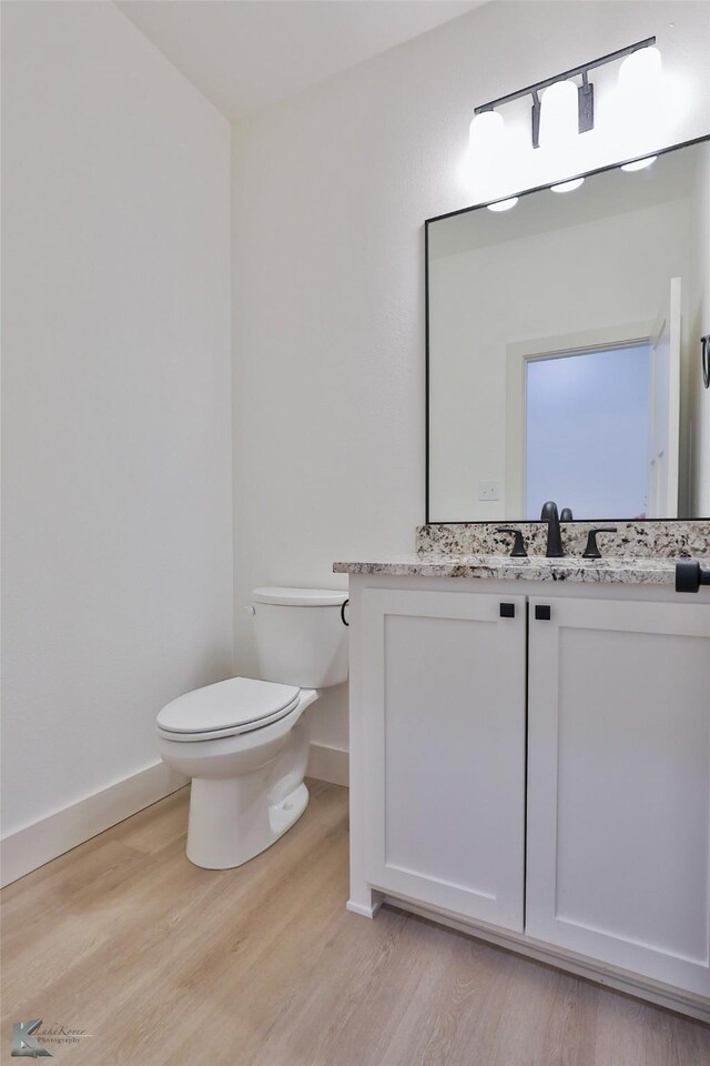 bathroom with toilet, hardwood / wood-style flooring, and vanity