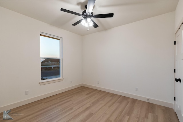 spare room featuring a ceiling fan, baseboards, and light wood finished floors