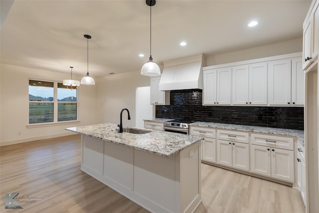 kitchen with electric stove, sink, white cabinets, and custom range hood