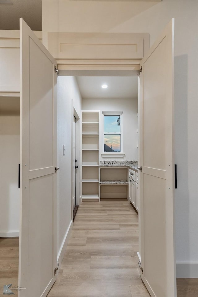 hallway featuring light wood-style floors, baseboards, and recessed lighting