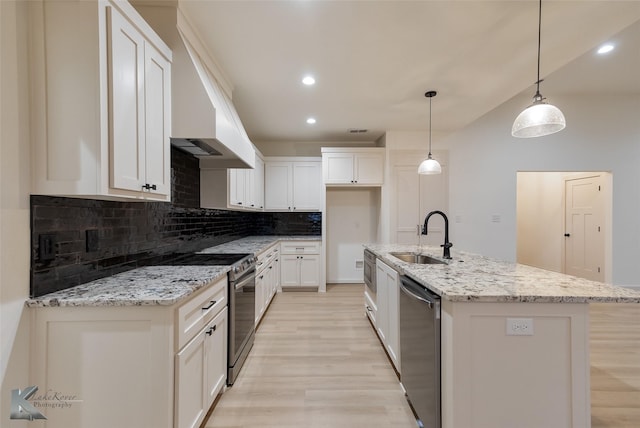 kitchen with a sink, white cabinets, appliances with stainless steel finishes, custom exhaust hood, and tasteful backsplash