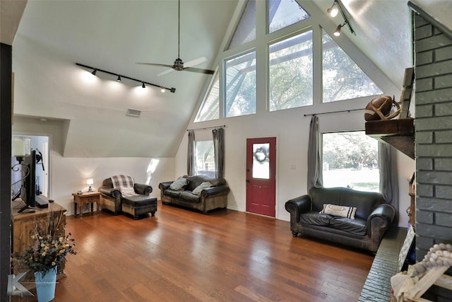 living room featuring high vaulted ceiling, dark wood-type flooring, ceiling fan, and a healthy amount of sunlight