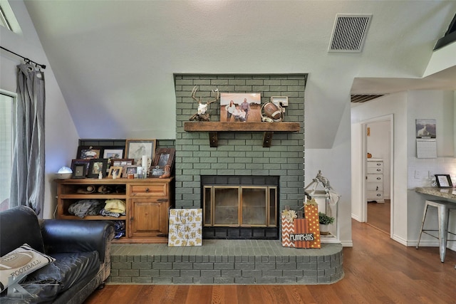 living room with vaulted ceiling, dark hardwood / wood-style floors, and a fireplace