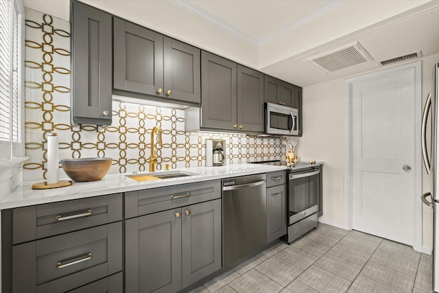 kitchen featuring tasteful backsplash, gray cabinets, sink, appliances with stainless steel finishes, and ornamental molding