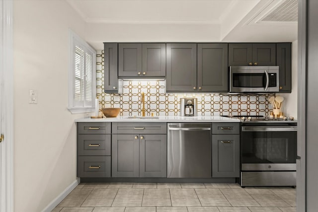 kitchen featuring sink, gray cabinetry, stainless steel appliances, and ornamental molding