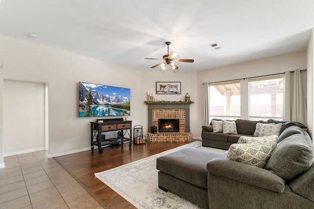 living room with ceiling fan, a brick fireplace, and hardwood / wood-style flooring