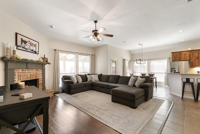 living room featuring light hardwood / wood-style flooring, ceiling fan, a fireplace, and plenty of natural light