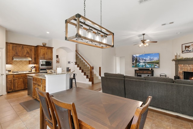 dining space featuring ceiling fan, light tile patterned flooring, and a fireplace