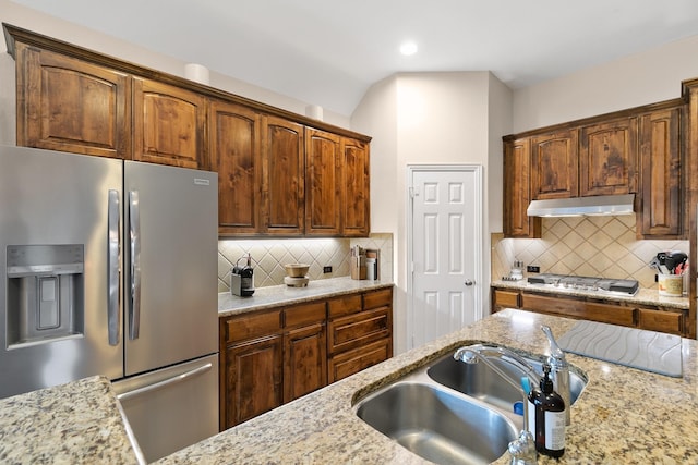 kitchen with light stone countertops, stainless steel appliances, backsplash, and sink