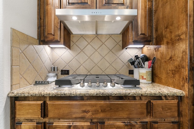 kitchen with stainless steel gas cooktop, tasteful backsplash, and light stone countertops