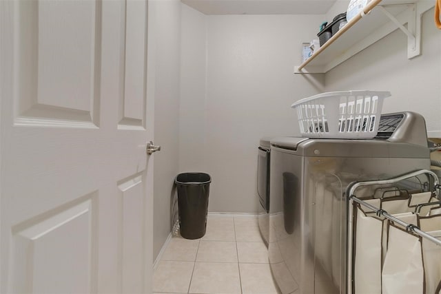 clothes washing area featuring light tile patterned flooring and washer and dryer