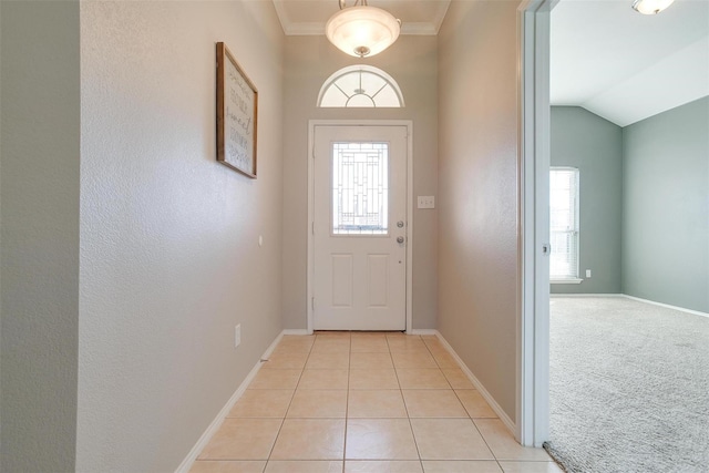 entryway featuring lofted ceiling, ornamental molding, and light tile patterned floors