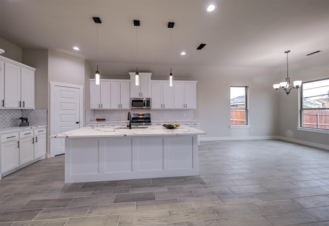 kitchen with white cabinetry, stainless steel appliances, and a center island with sink