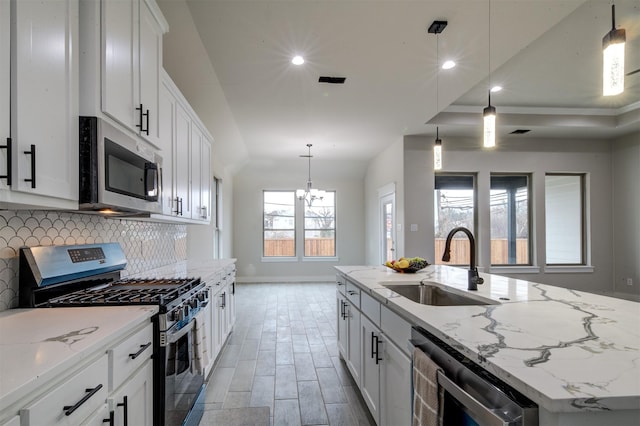 kitchen featuring stainless steel appliances, white cabinetry, and a kitchen island with sink