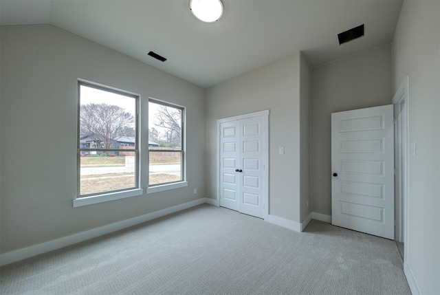 unfurnished bedroom with light carpet, lofted ceiling, and a closet