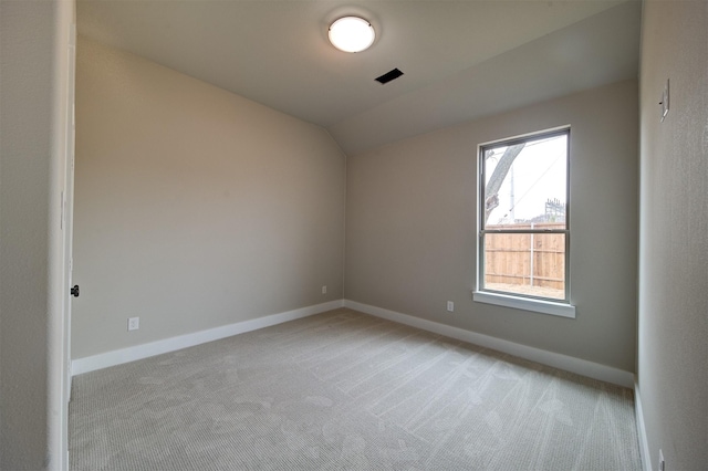 unfurnished room featuring lofted ceiling and light carpet