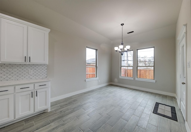 unfurnished dining area with a notable chandelier and light hardwood / wood-style floors