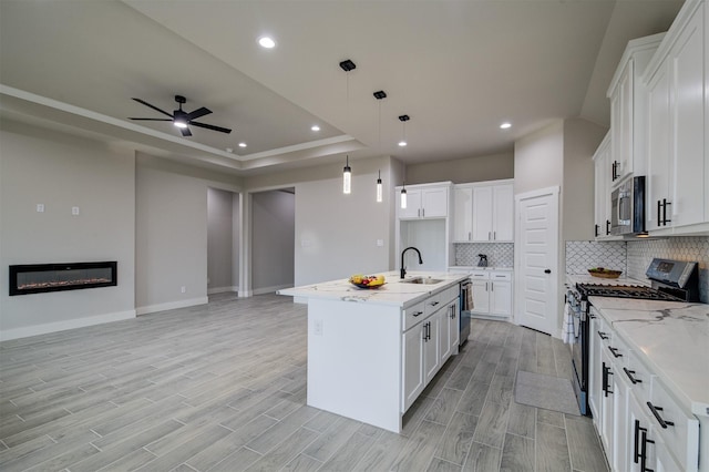 kitchen featuring appliances with stainless steel finishes, a kitchen island with sink, and white cabinets