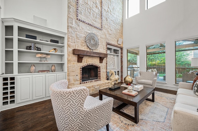 living room featuring a stone fireplace, a high ceiling, and wood finished floors