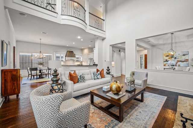 living room featuring dark hardwood / wood-style flooring, a towering ceiling, and a notable chandelier