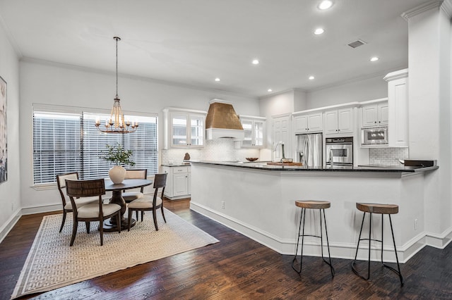 kitchen featuring pendant lighting, white cabinetry, appliances with stainless steel finishes, and dark hardwood / wood-style flooring