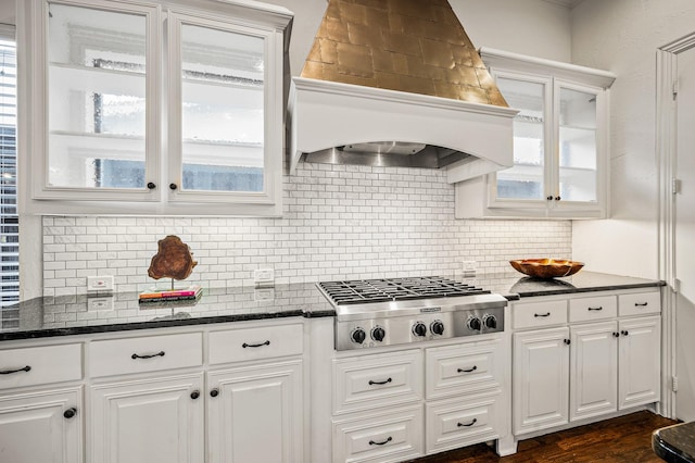 kitchen featuring stainless steel gas stovetop, premium range hood, tasteful backsplash, dark stone counters, and white cabinets