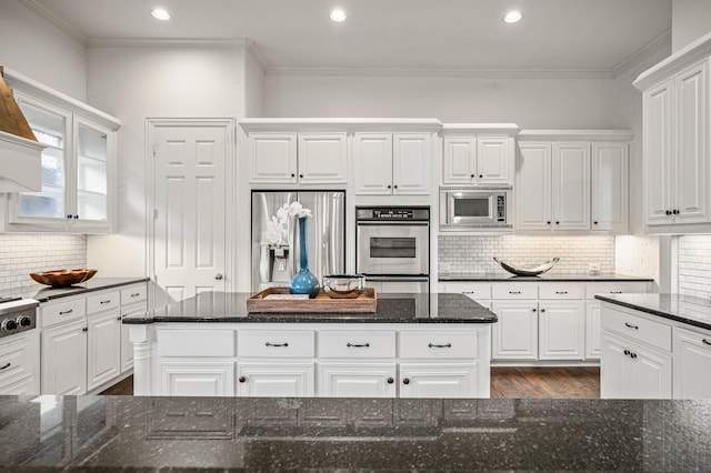 kitchen featuring crown molding, stainless steel appliances, dark wood-type flooring, white cabinetry, and dark stone countertops