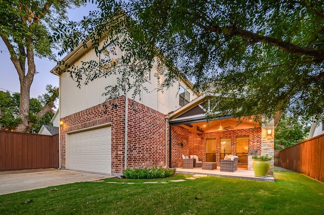 exterior space with concrete driveway, brick siding, fence, and an outdoor living space