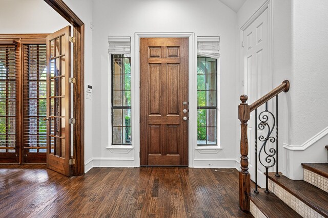 entryway featuring plenty of natural light, stairway, wood-type flooring, and vaulted ceiling