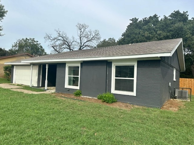 back of property featuring a garage, a yard, and central AC