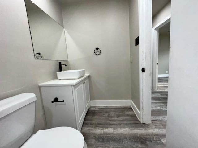 bathroom with toilet, hardwood / wood-style flooring, and vanity