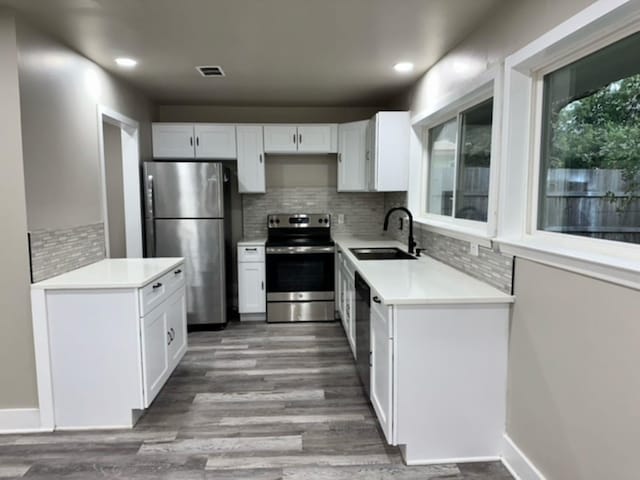 kitchen featuring decorative backsplash, sink, white cabinets, and appliances with stainless steel finishes