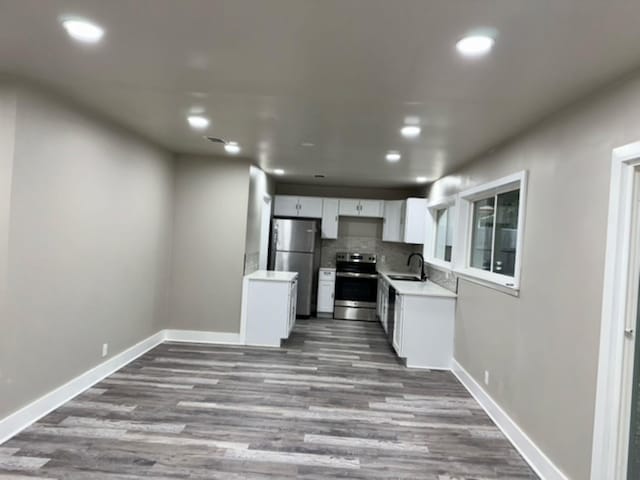 kitchen with appliances with stainless steel finishes, tasteful backsplash, dark hardwood / wood-style flooring, white cabinets, and sink