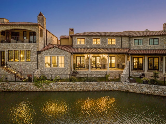 back house at dusk featuring a water view