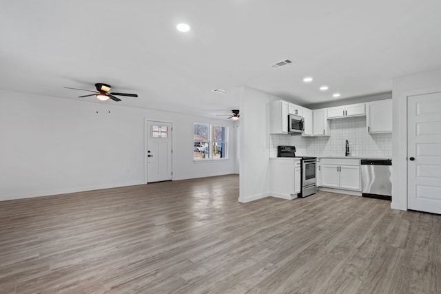 kitchen featuring light hardwood / wood-style flooring, ceiling fan, backsplash, stainless steel appliances, and white cabinets