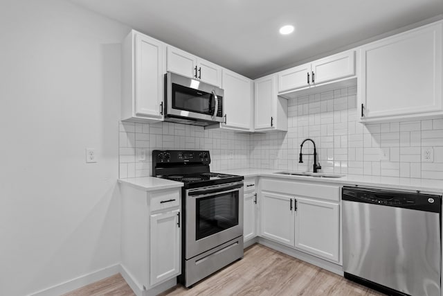 kitchen with light wood-type flooring, stainless steel appliances, sink, and white cabinets