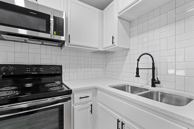 kitchen with electric range oven, sink, and white cabinets