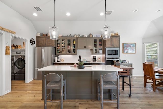 kitchen with lofted ceiling, appliances with stainless steel finishes, a kitchen breakfast bar, and pendant lighting