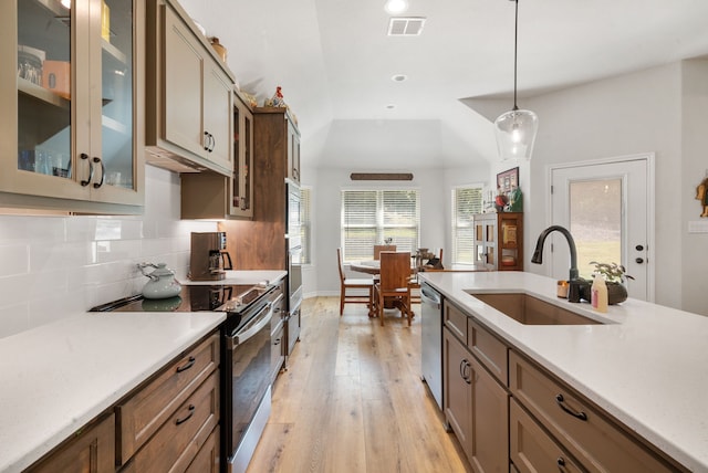 kitchen with appliances with stainless steel finishes, tasteful backsplash, sink, hanging light fixtures, and light hardwood / wood-style flooring