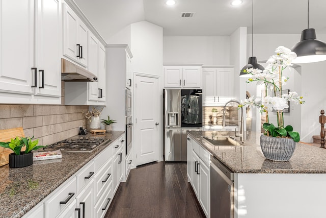 kitchen featuring white cabinets, decorative light fixtures, stainless steel appliances, dark stone countertops, and sink